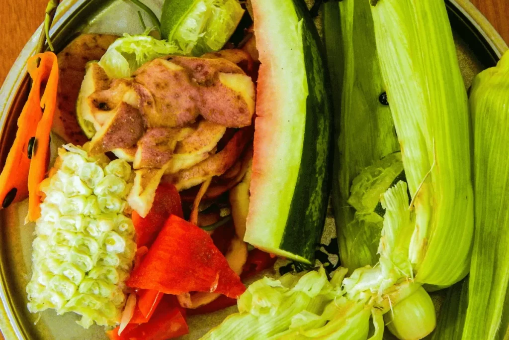 Kitchen scraps including corn cobs, watermelon rind, potato peels, bell peppers, and lettuce—ideal organic materials for creating square foot garden compost.