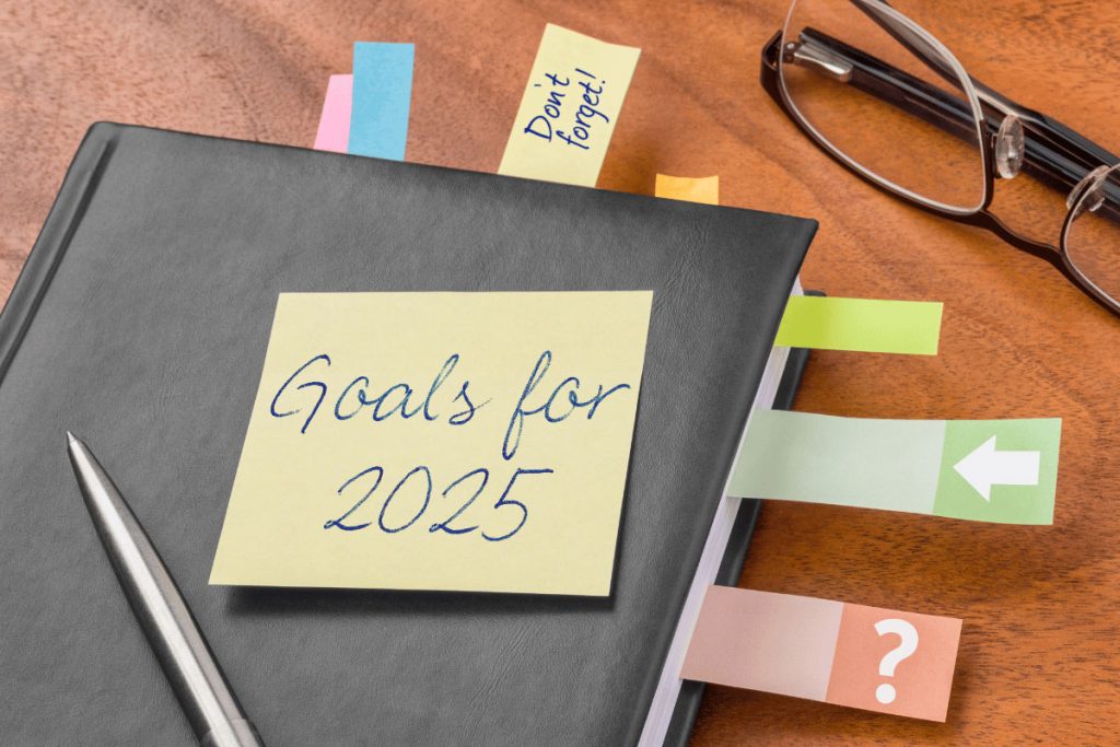 Notebook labeled “Goals for 2025” with colorful tabs and a pen, resting on a desk—symbolizing planning, focus, and execution of new year resolution ideas.
